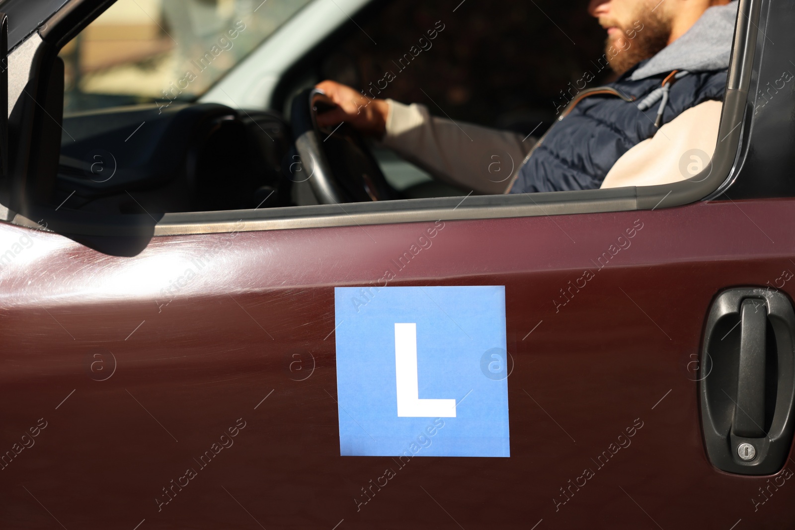 Photo of Learner driver driving car with L-plate, view from outside. Driving school