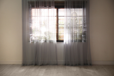 Photo of Window with beautiful curtains and blinds in empty room