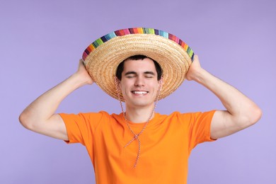 Photo of Young man in Mexican sombrero hat on violet background
