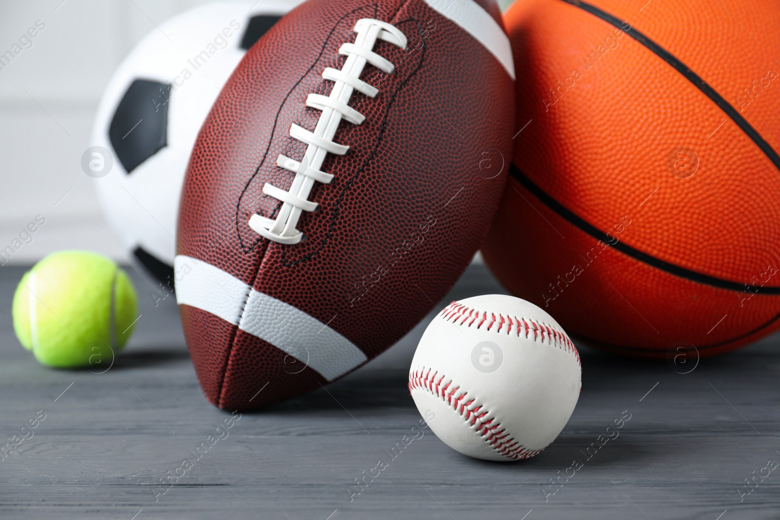 Photo of Set of different sport balls on grey wooden table, closeup