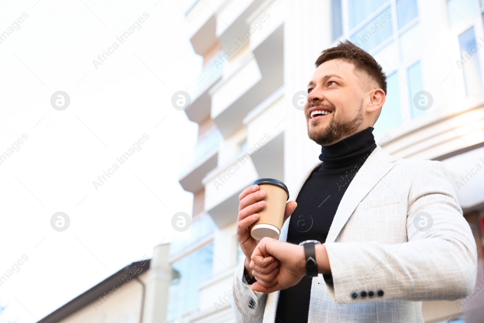 Photo of Businessman with cup of coffee on city street in morning