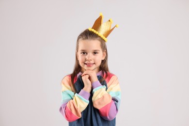 Photo of Cute girl in golden crown on light grey background. Little princess