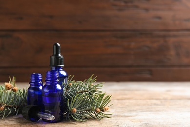 Photo of Composition with bottles of conifer essential oil on wooden table. Space for text