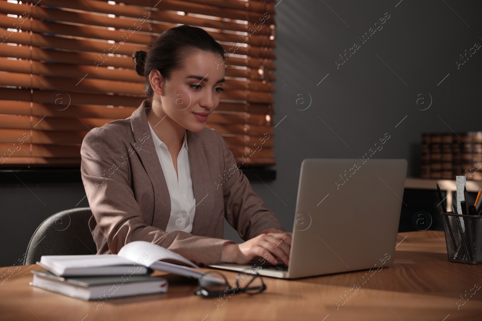 Photo of Woman working with laptop at wooden desk in office