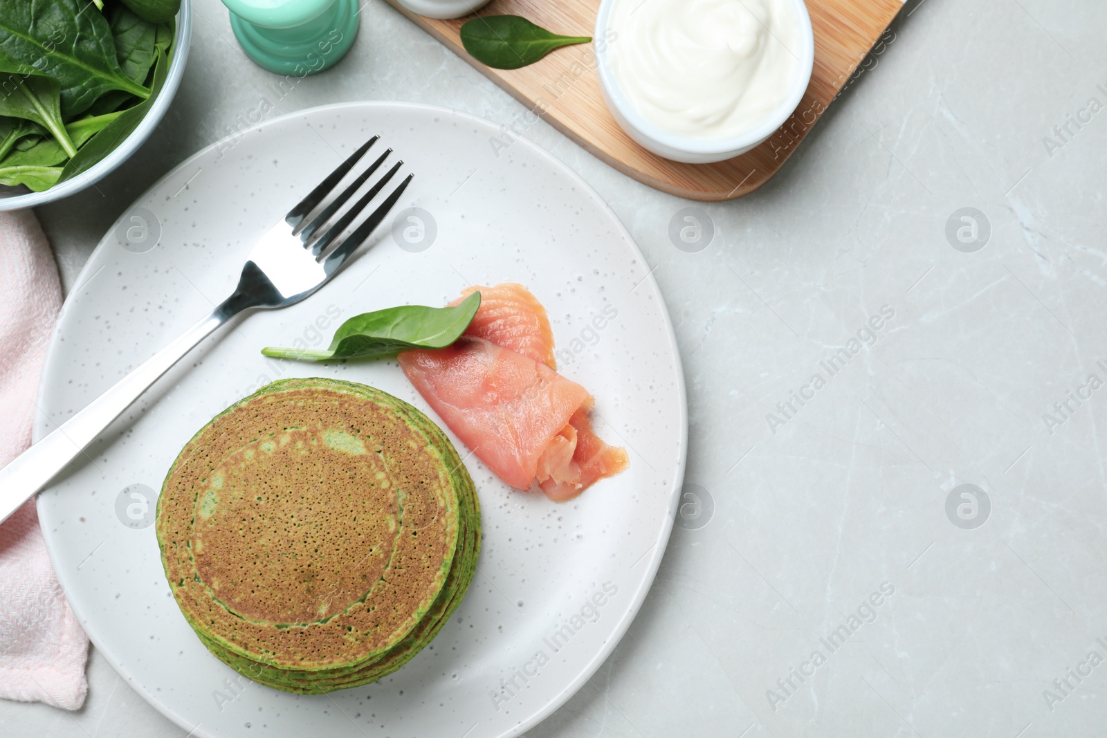 Photo of Tasty spinach pancakes served on light grey marble table, flat lay. Space for text