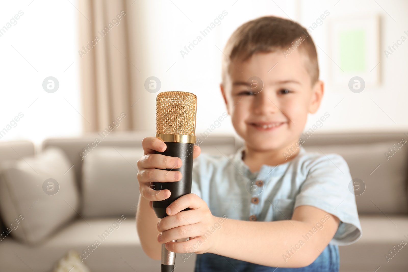 Photo of Cute funny boy with microphone in living room