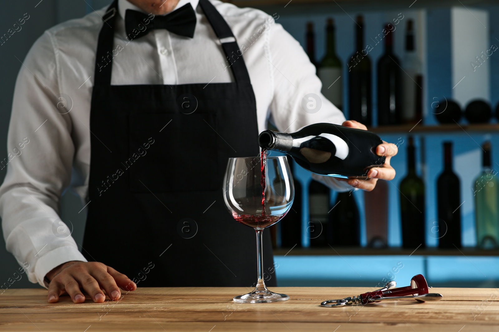 Photo of Bartender pouring wine into glass at counter in restaurant, closeup
