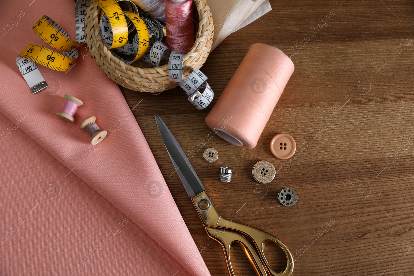 Photo of Set of sewing supplies and accessories on wooden table, flat lay