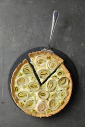 Photo of Tasty leek pie with cake server on dark textured table, top view