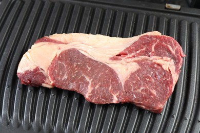 Photo of Cooking fresh beef cut on electric grill, closeup