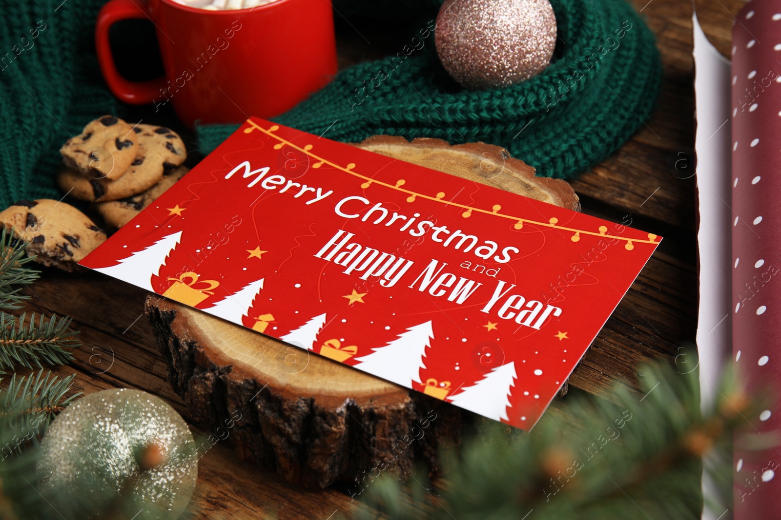 Photo of Greeting card and Christmas balls on wooden table, closeup