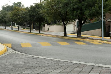 Photo of City street with striped concrete speed bump
