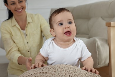 Photo of Happy mother with her cute baby near sofa at home