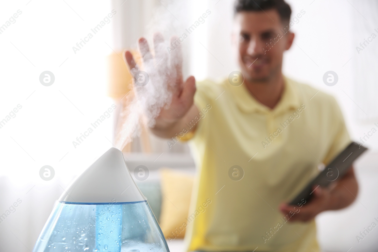 Photo of Man near modern air humidifier at home