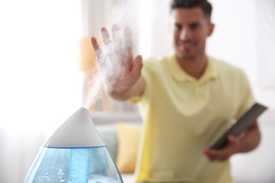 Man near modern air humidifier at home