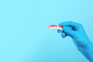 Photo of Dentist holding teeth cover on color background. Space for text