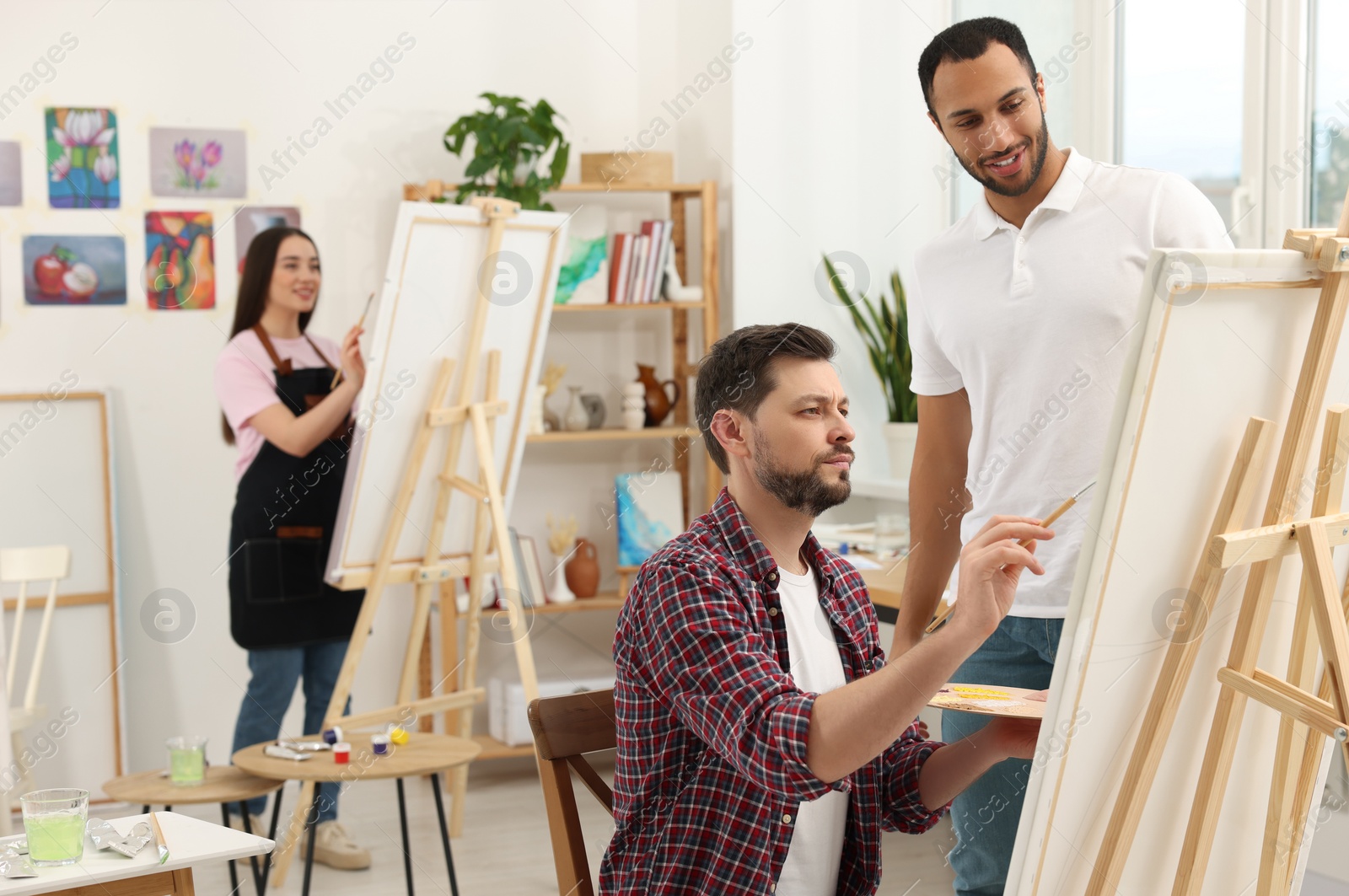 Photo of Artist and her students having painting class in studio. Creative hobby