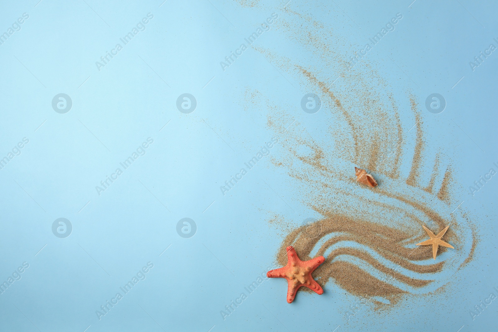 Photo of Beautiful starfishes, sea shell and sand on light blue background, flat lay. Space for text