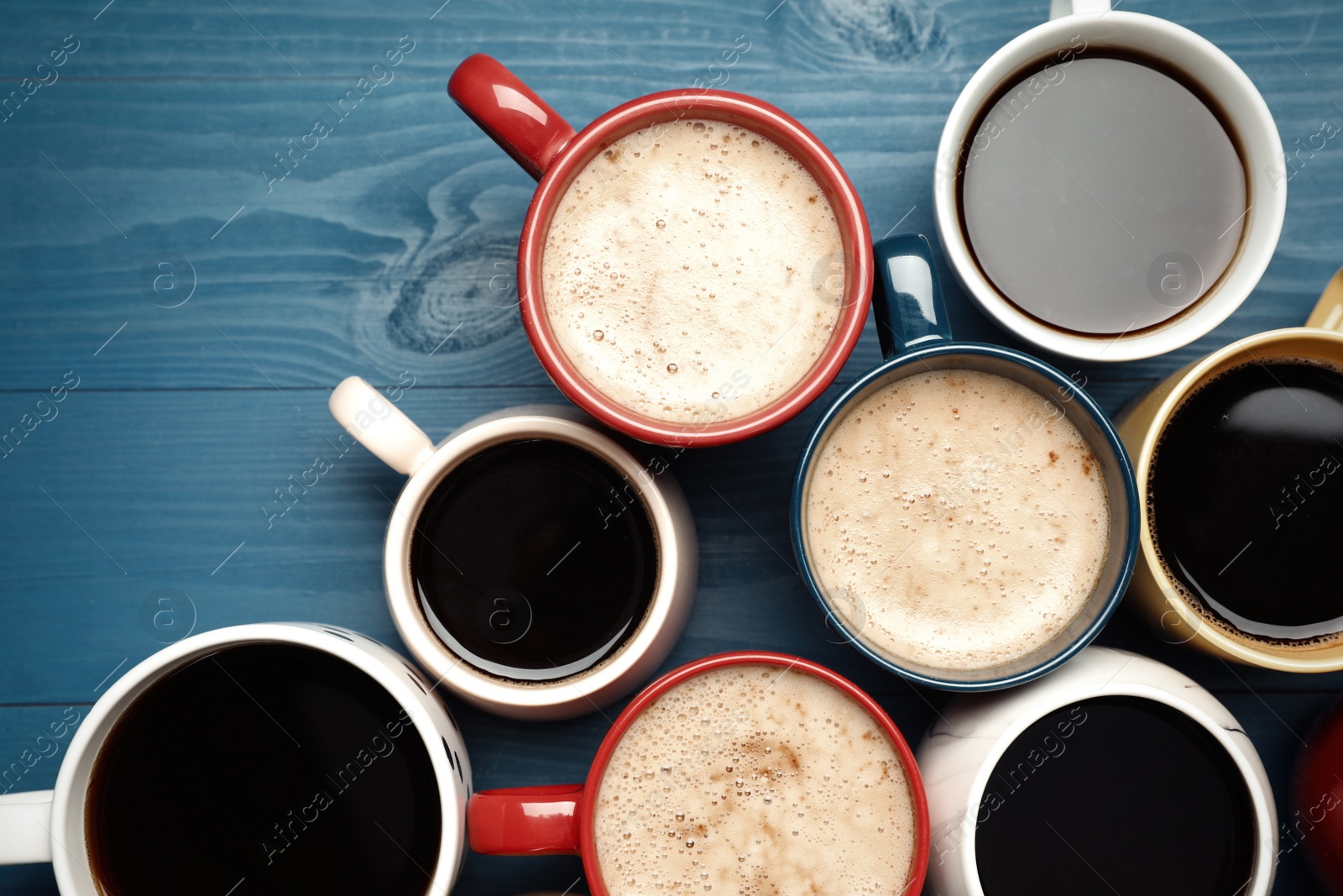 Photo of Many cups of different coffee drinks on blue wooden table, flat lay