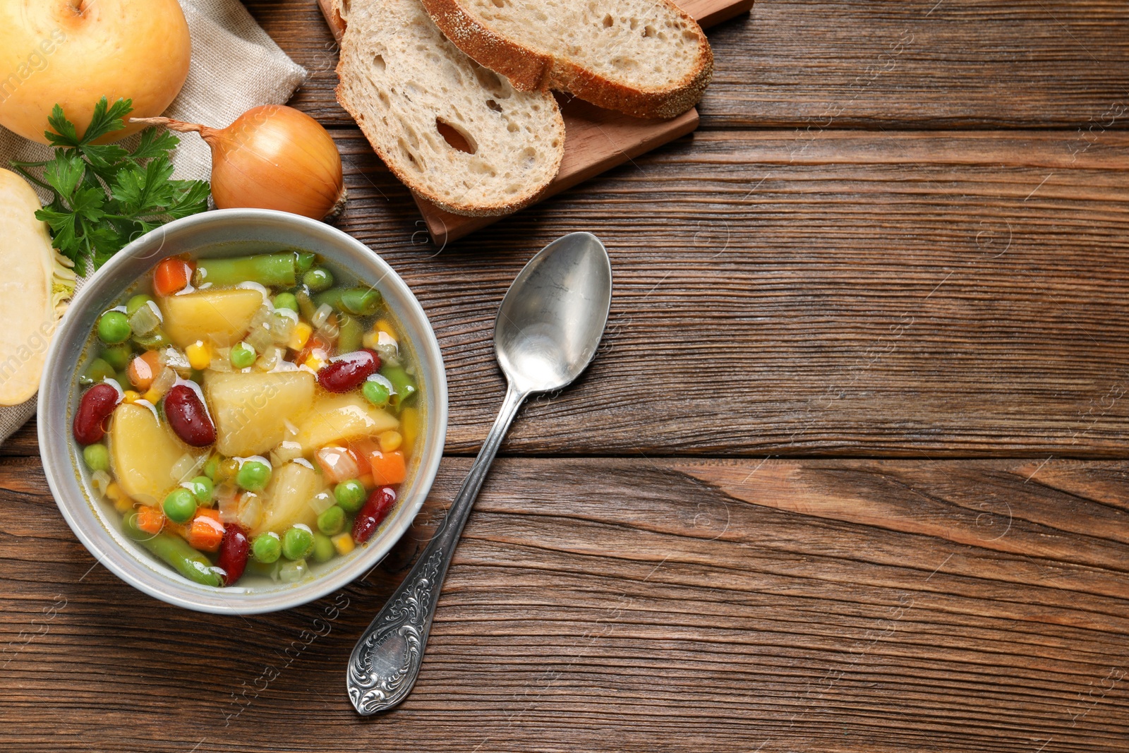 Photo of Bowl of delicious turnip soup served on wooden table, flat lay. Space for text