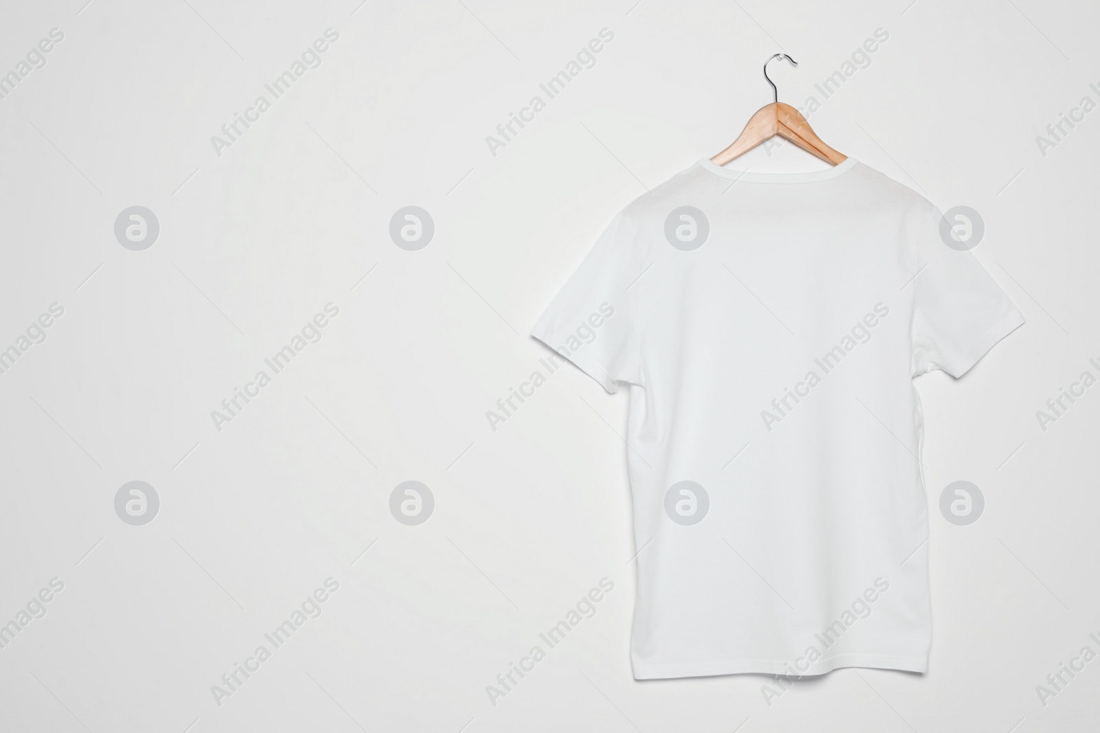 Photo of Hanger with blank t-shirt on white background. Mock up for design