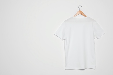 Photo of Hanger with blank t-shirt on white background. Mock up for design