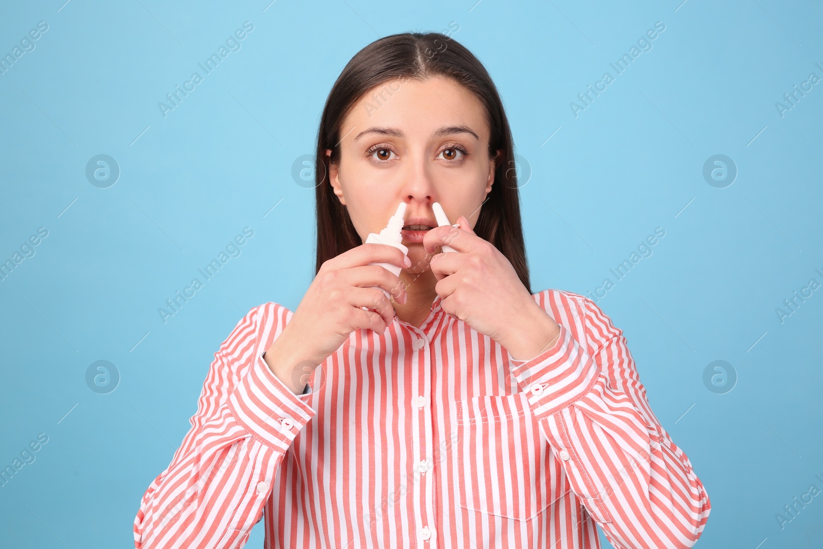 Photo of Woman using nasal sprays on light blue background