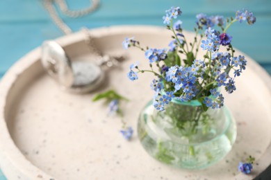 Photo of Beautiful Forget-me-not flowers in vase on tray