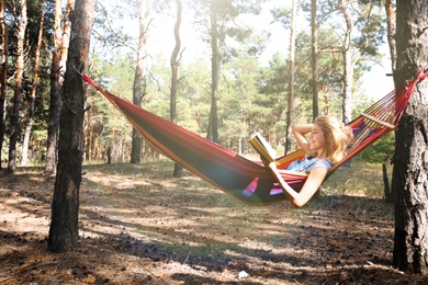 Photo of Woman with book relaxing in hammock outdoors on summer day