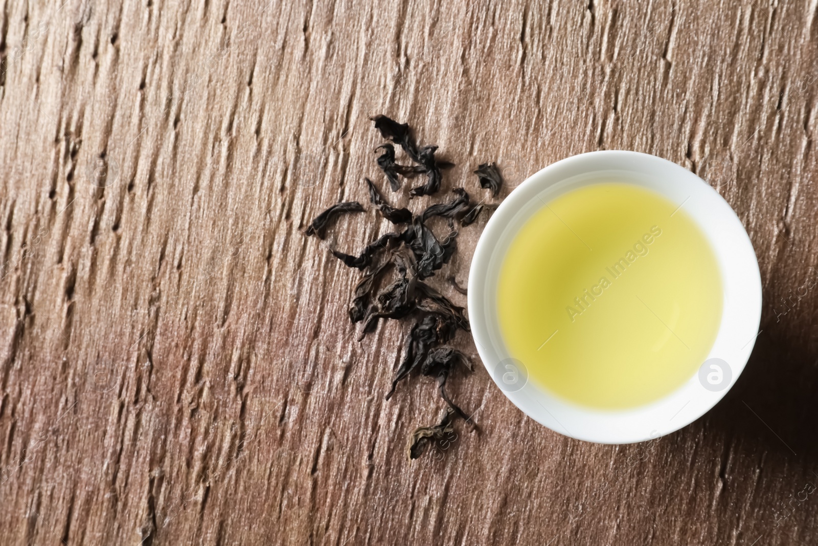 Photo of Cup of Da Hong Pao oolong and tea leaves on table, top view with space for text