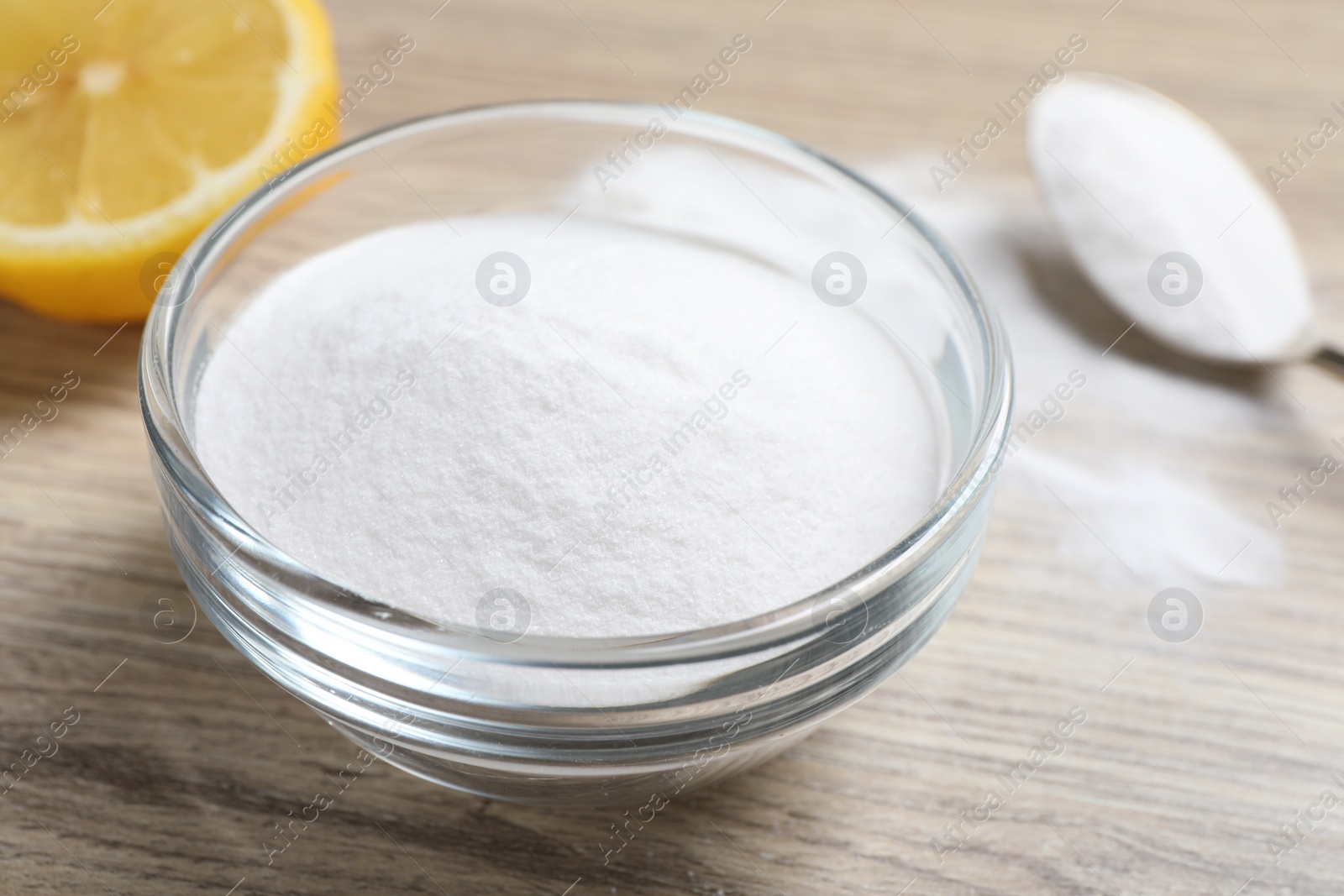 Photo of Baking soda and lemon on wooden table, closeup