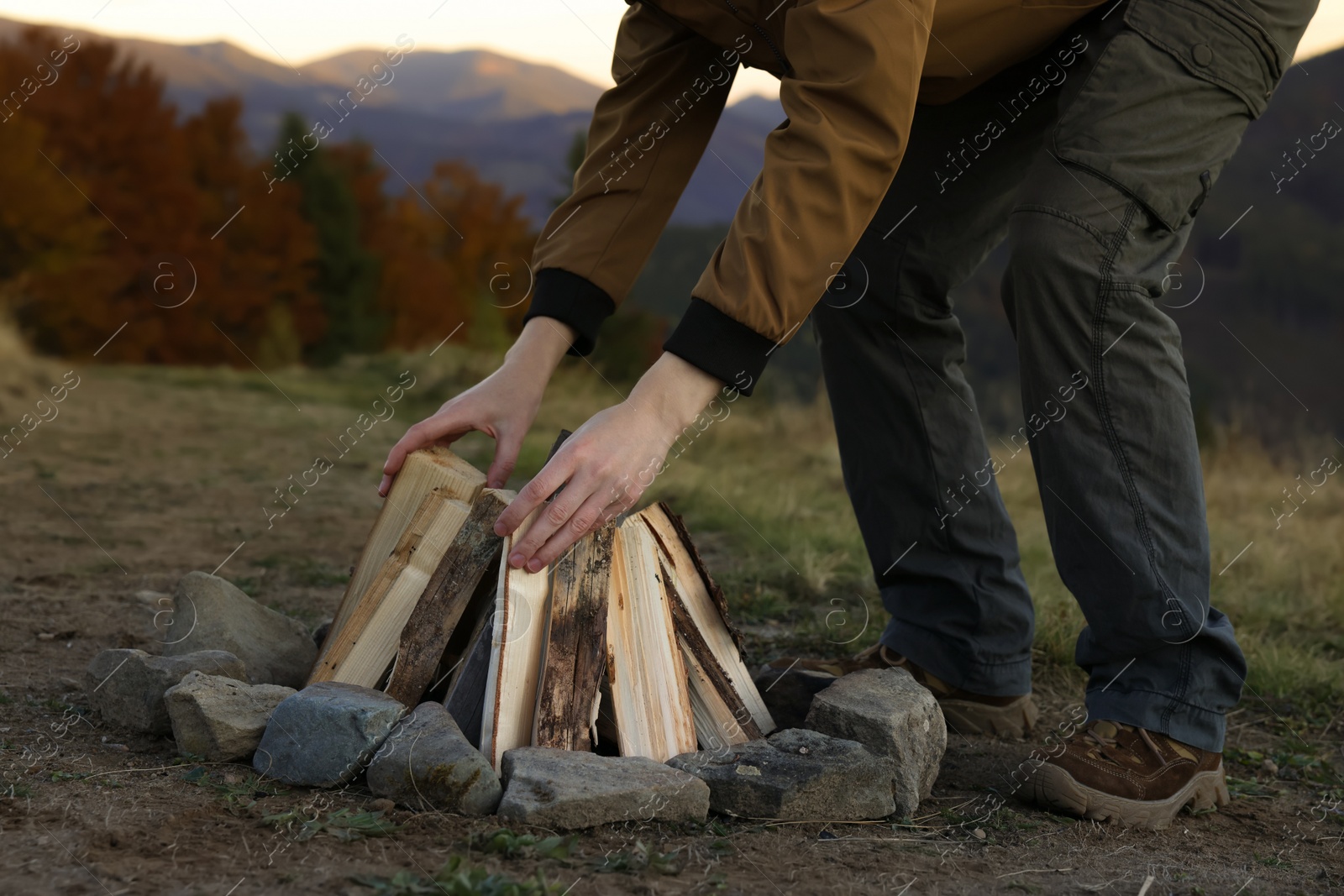 Photo of Traveler making bonfire with dry wood outdoors, closeup