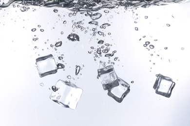 Photo of Ice cubes falling into water against white background