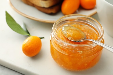 Photo of Delicious kumquat jam in glass jar on white board