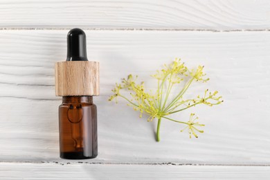 Bottle of essential oil and fresh dill on white wooden table, flat lay