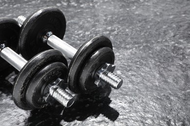 Photo of Two barbells on dark textured floor, closeup. Space for text