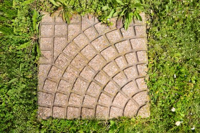 Photo of Fresh green grass and stone tiles outdoors, top view