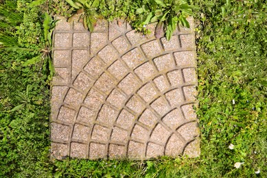 Fresh green grass and stone tiles outdoors, top view