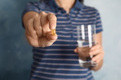 Woman with fish oil pill and glass of water, closeup