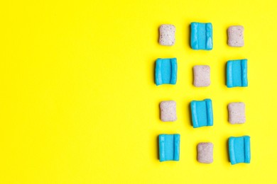 Photo of Different bubble gums on yellow background, flat lay. Space for text