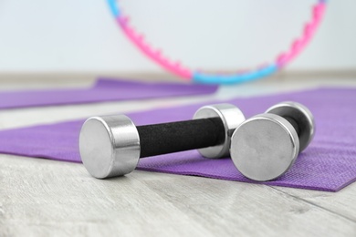 Photo of Dumbbells on fitness mat in physiotherapy gym, closeup