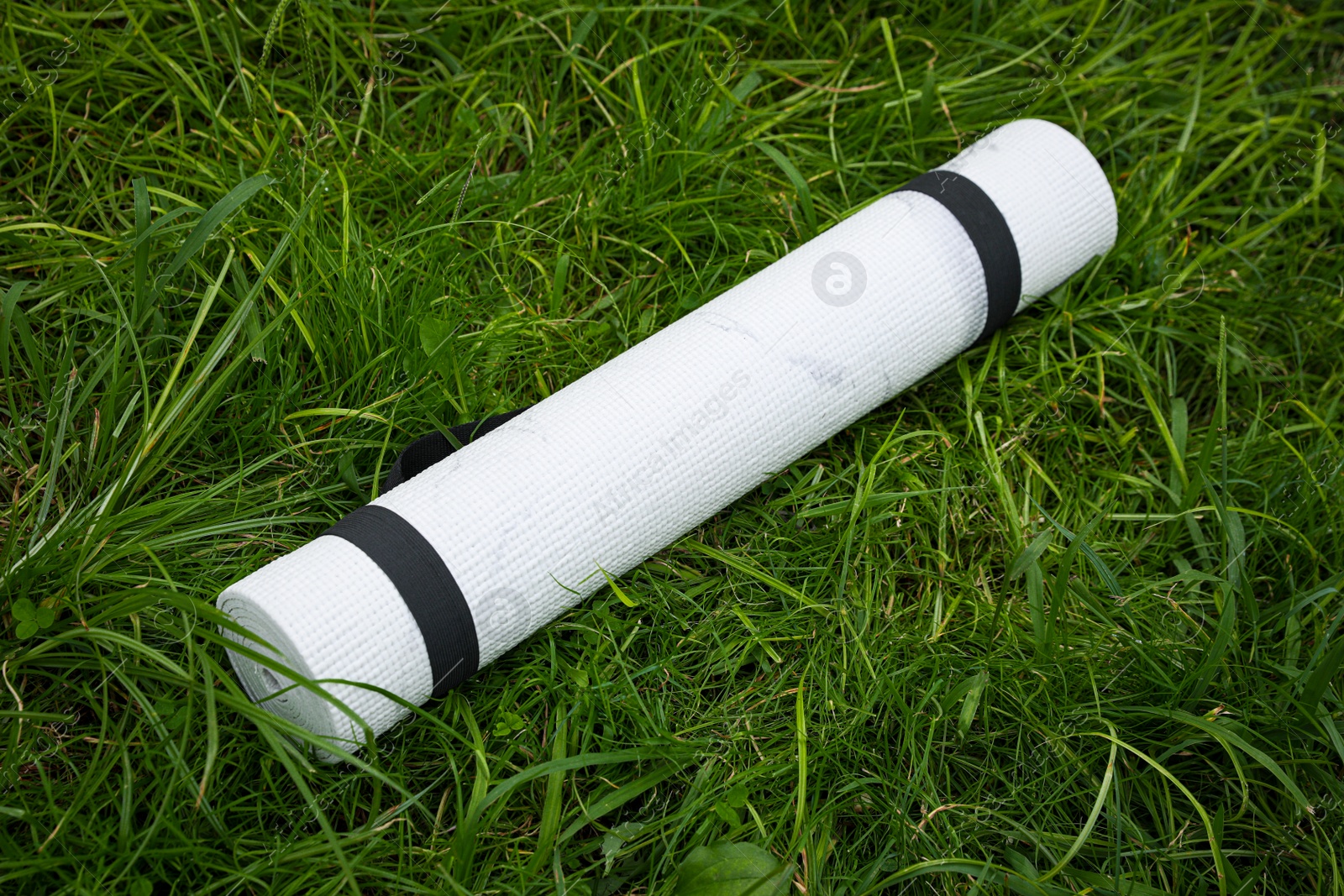 Photo of White karemat or fitness mat on green grass outdoors