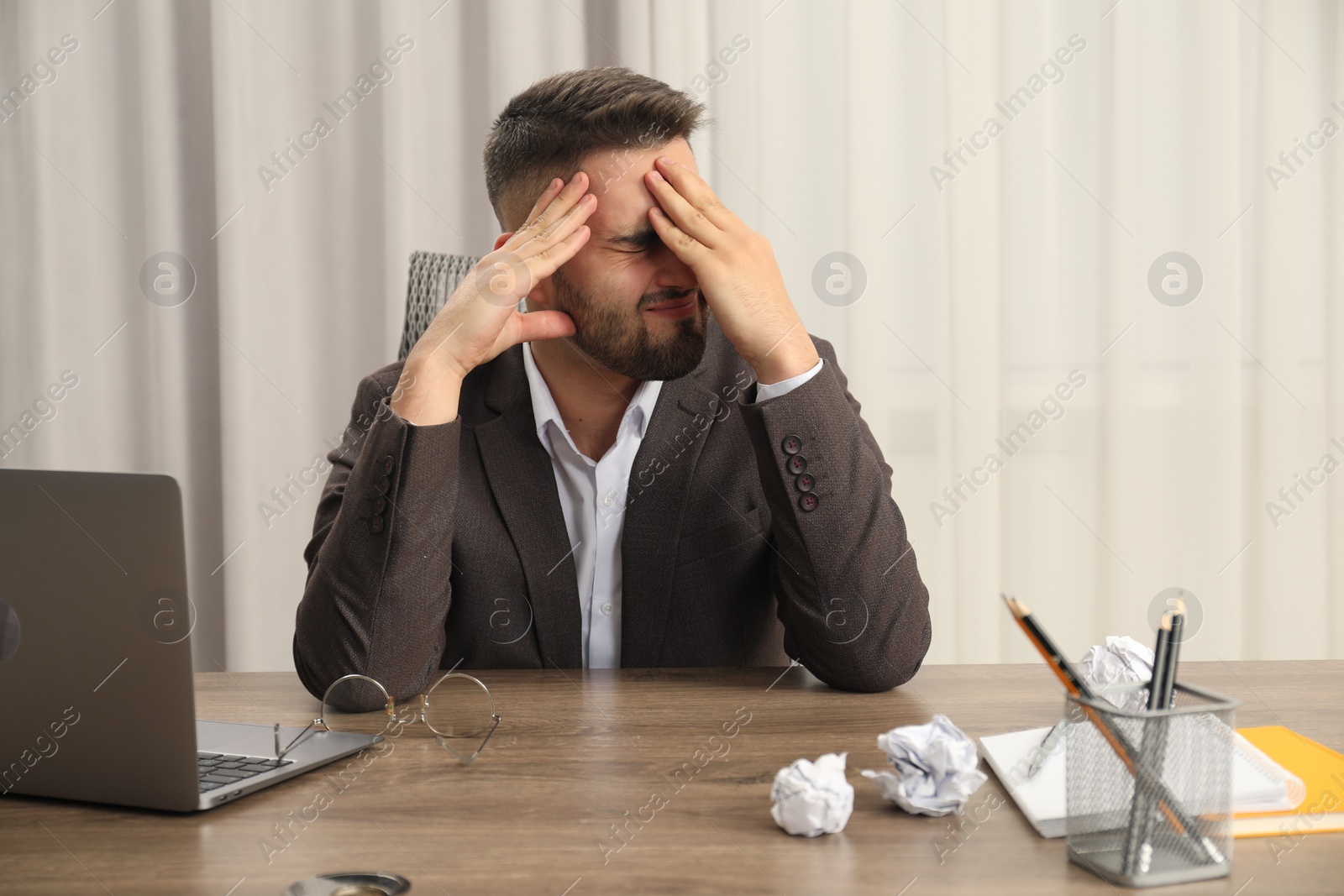 Photo of Tired sad businessman sitting at table in office