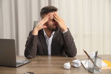 Photo of Tired sad businessman sitting at table in office