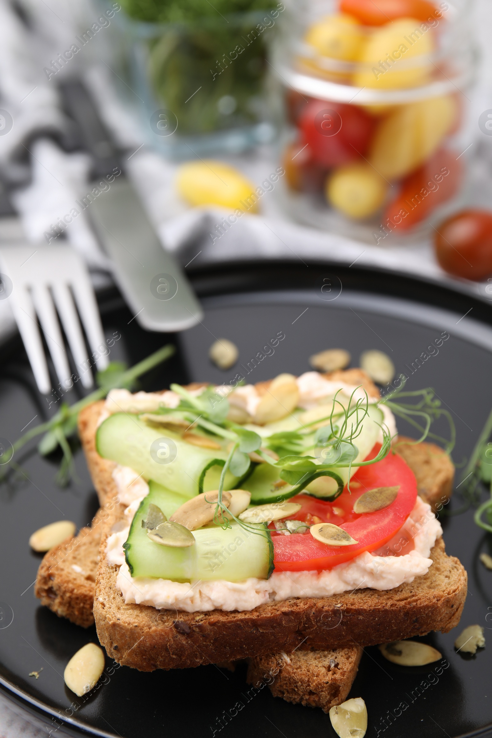 Photo of Tasty vegan sandwich with cucumber, tomato and pumpkin seeds on table, closeup