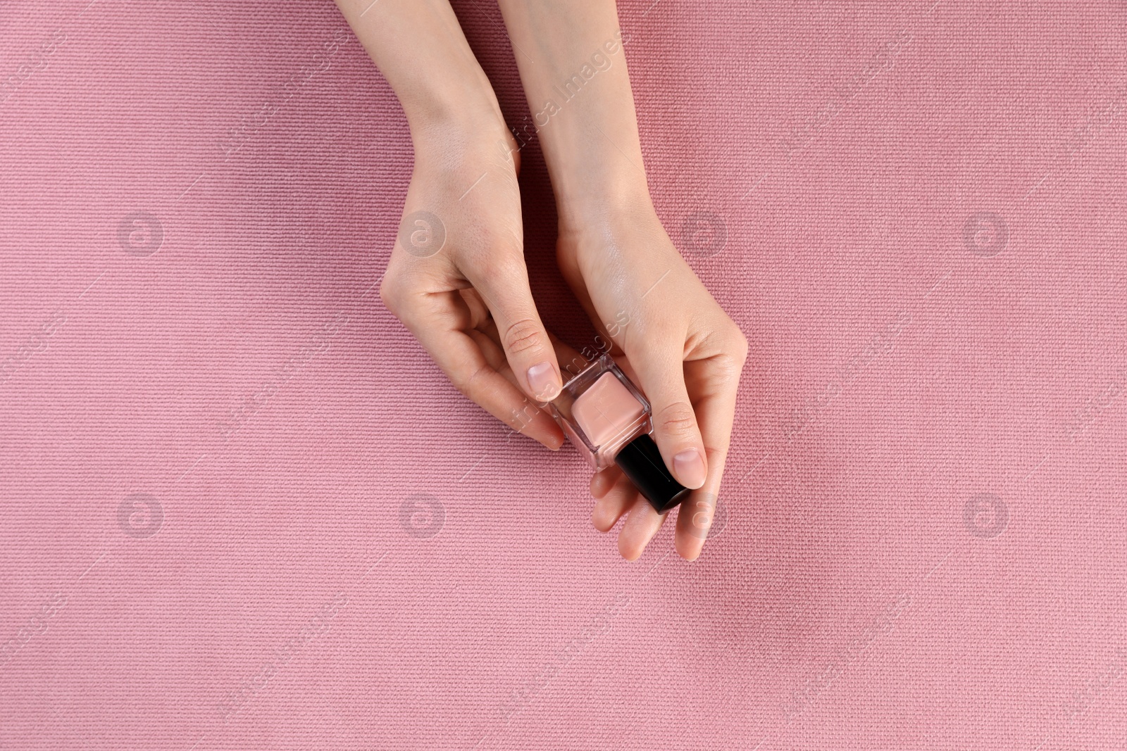 Photo of Woman with nail polish on pink fabric, closeup of hands