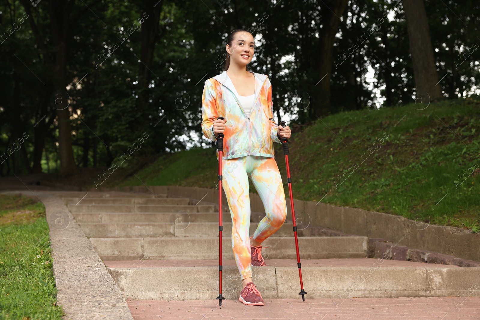 Photo of Young woman practicing Nordic walking with poles on steps outdoors
