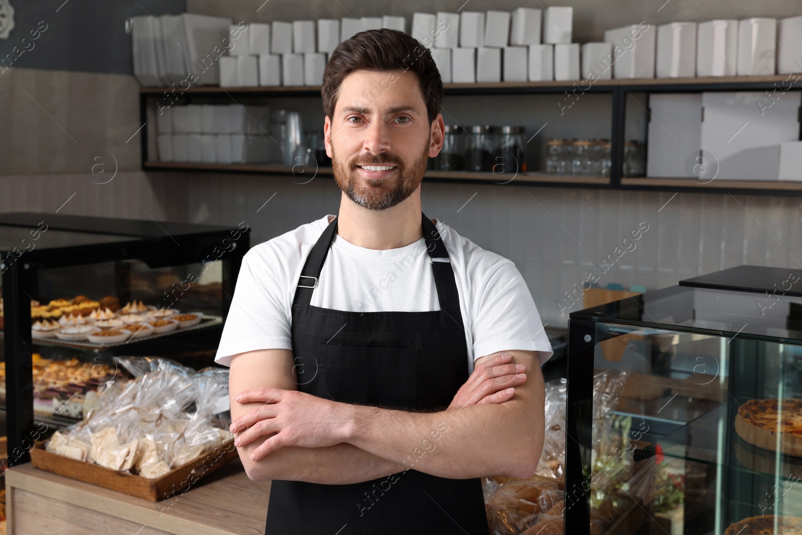 Photo of Happy seller near showcase in bakery shop