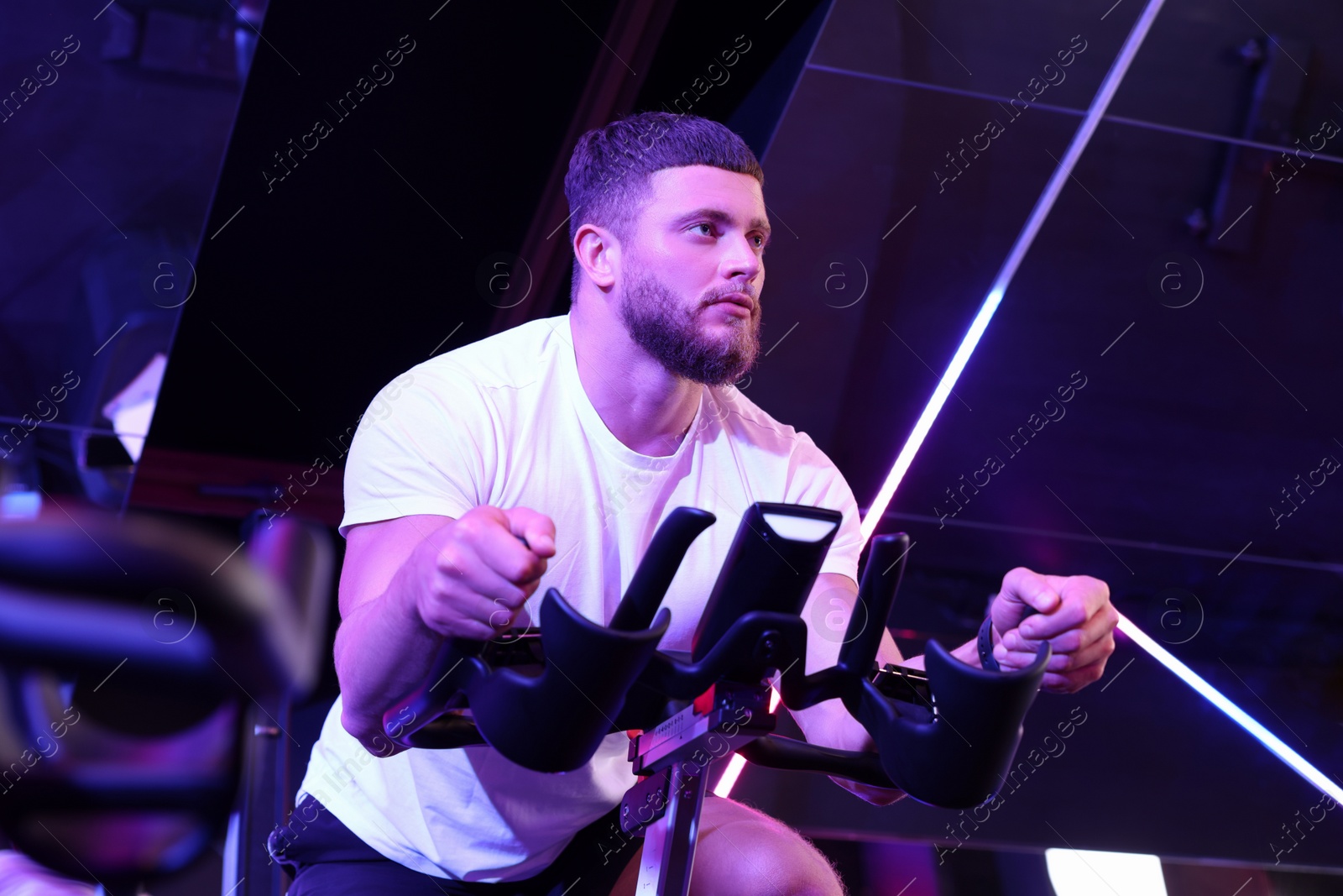 Photo of Young man training on exercise bike in fitness club