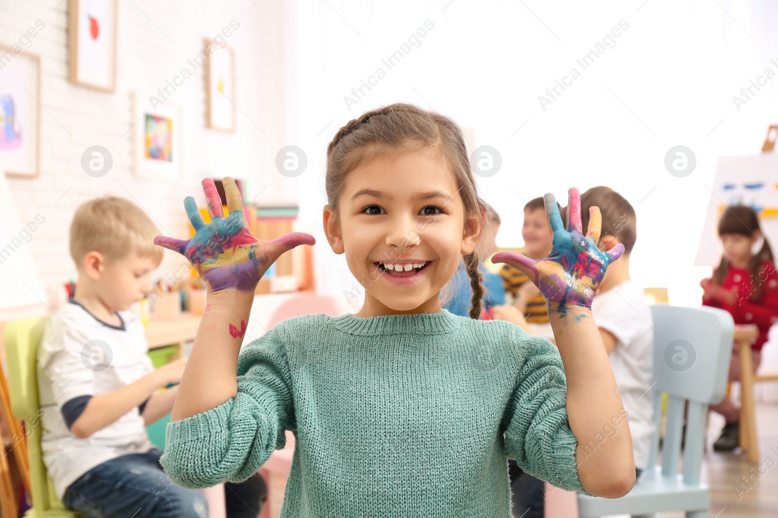 Photo of Cute little child with painted palms in room